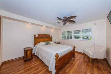 Second bedroom with plantation shutters, custom ceiling fan, laminate flooring and hurricane windows