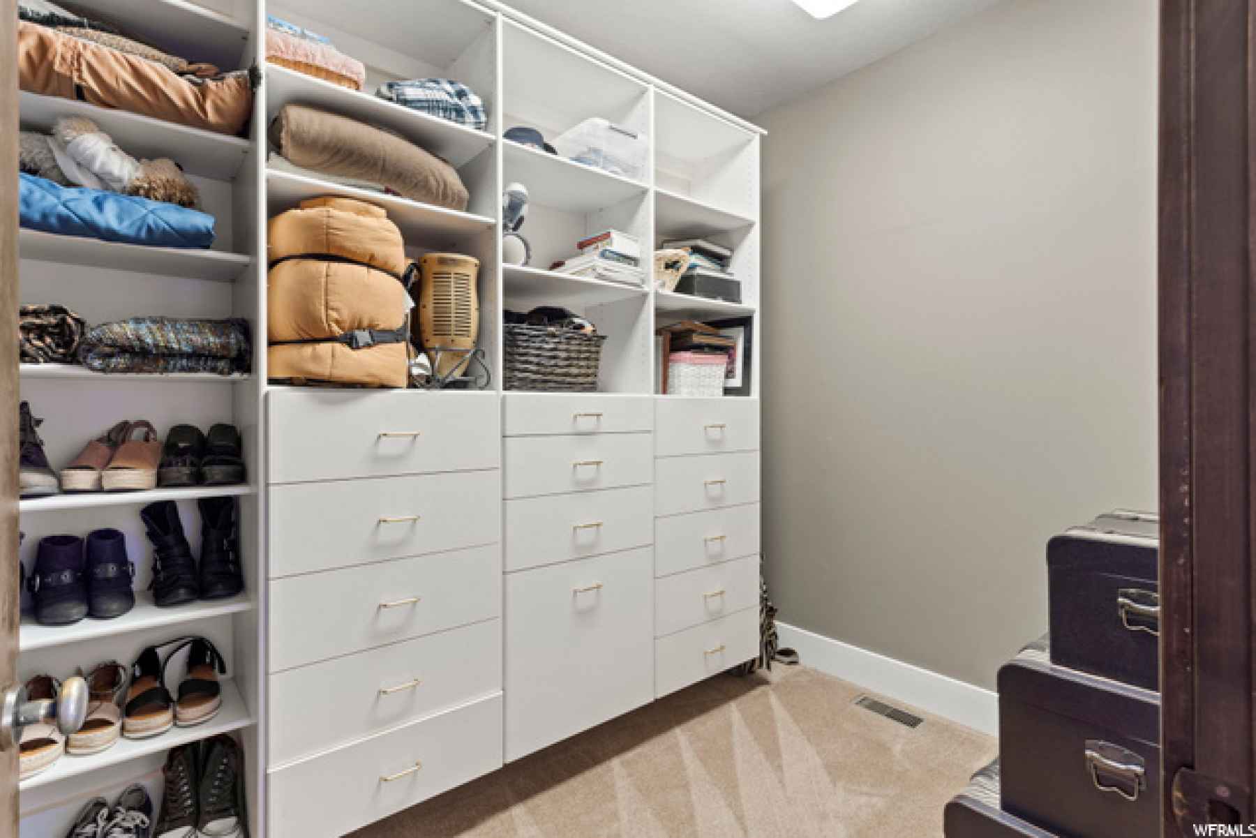 The window adds plenty of light in this primary walk in closet with loads of built ins to house your entire wardrobe!
