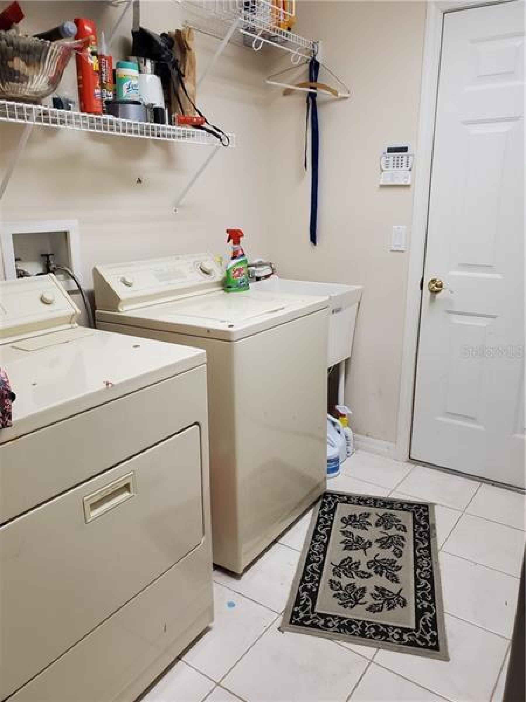 Laundry Room with washer/dryer, sink and racks. Door leads to 3-car garage