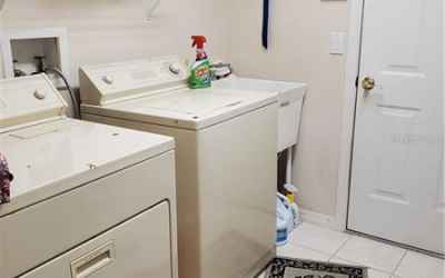 Laundry Room with washer/dryer, sink and racks. Door leads to 3-car garage