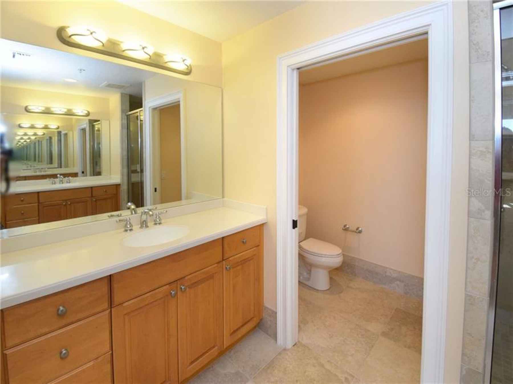Master bath with dual vanities with Corian countertops, and water closet.