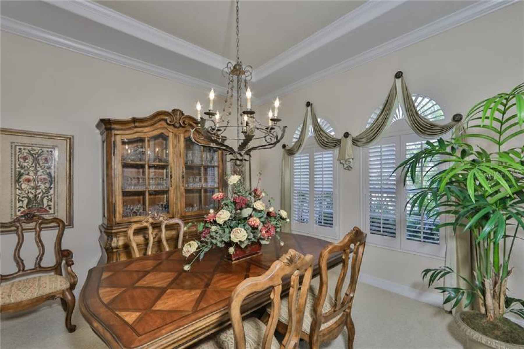 The Dining room boasts of plantation shutters, crown molding and a tray ceiling.