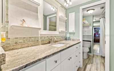 Gorgeous updated guest bathroom featuring a large granite counter top, custom back splash, wood look
