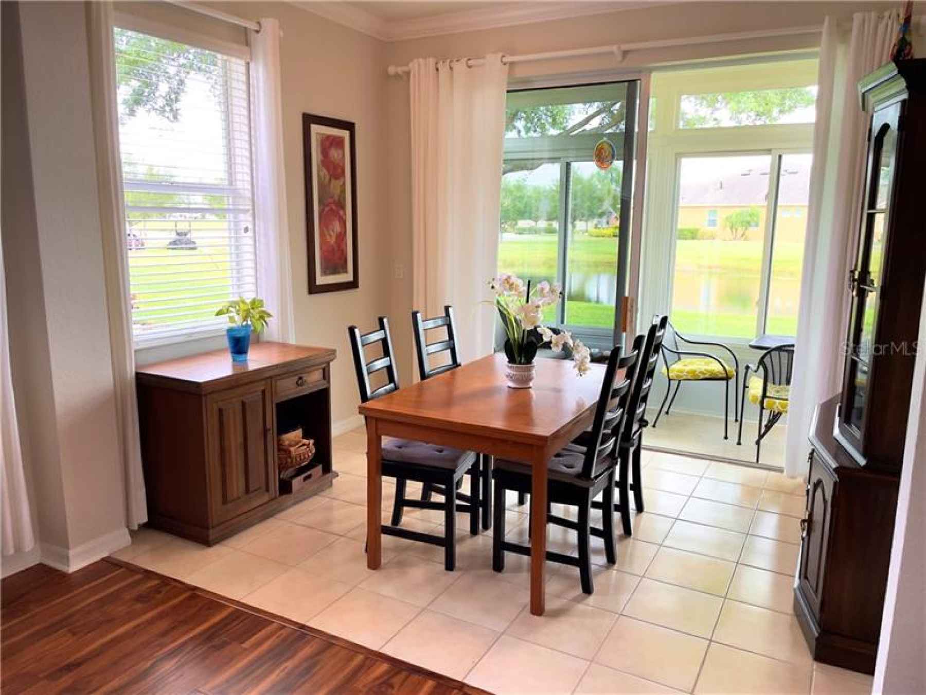 Dining room with view of enclosed lanai and pond.