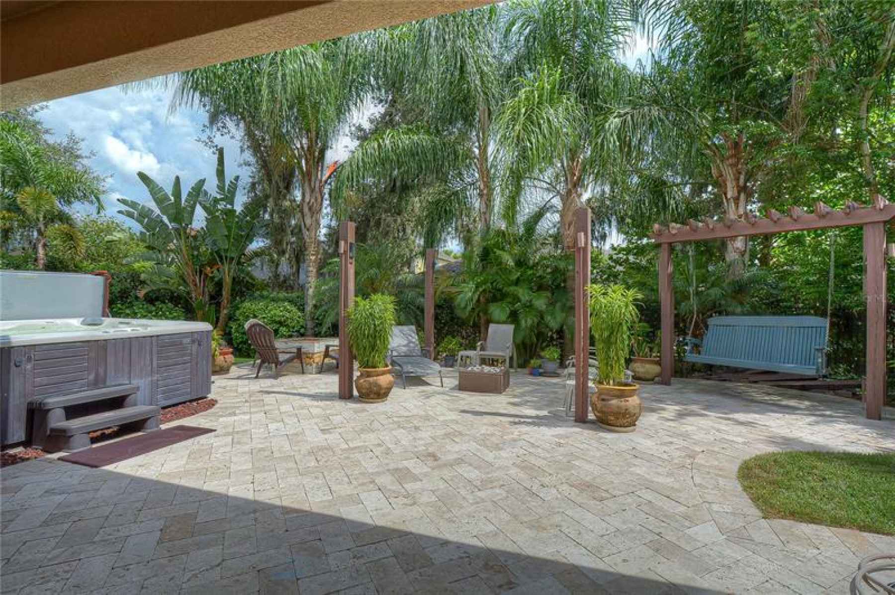 Gorgeous travertine pavers create a magnificent lanai space with a custom fire pit area and bench sw