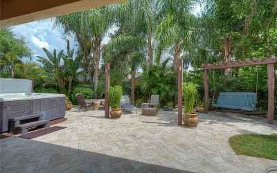 Gorgeous travertine pavers create a magnificent lanai space with a custom fire pit area and bench sw