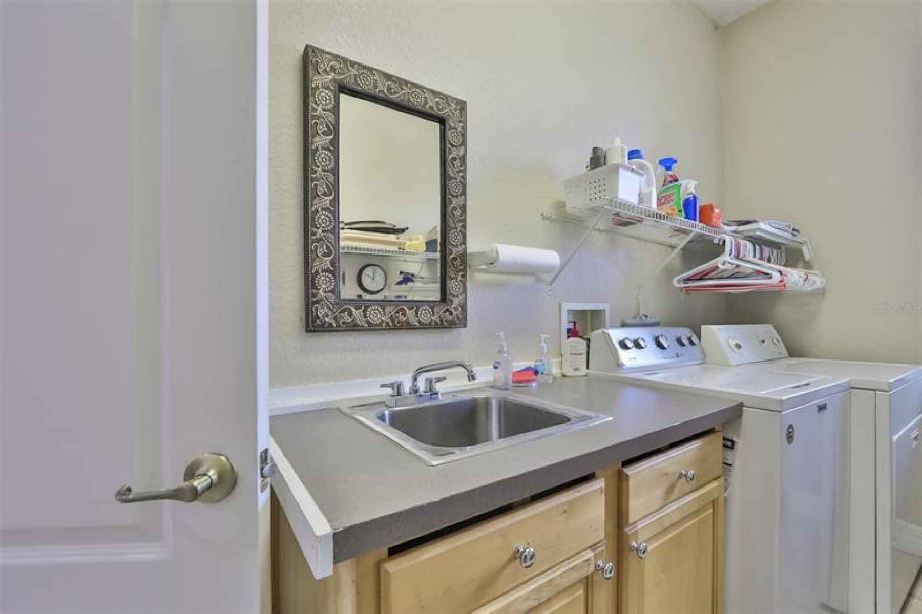 Private laundry room with sink and storage also includes garage door entrance.