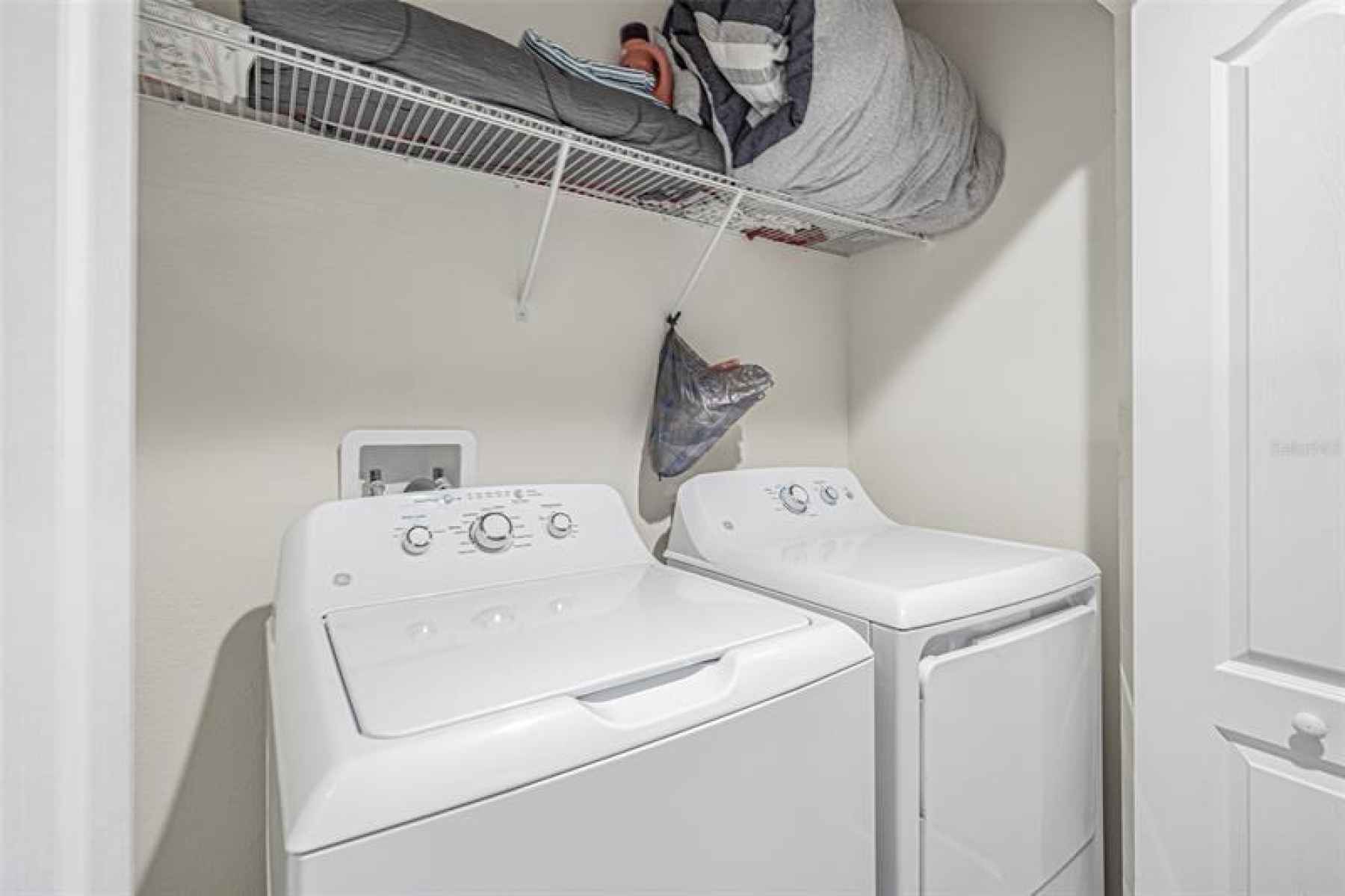 Large GE washer & dryer closet with extra storage space.