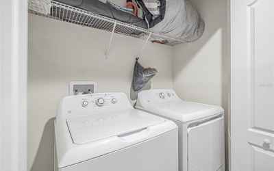 Large GE washer & dryer closet with extra storage space.