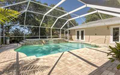 The large pool deck is screened and features light colored pavers