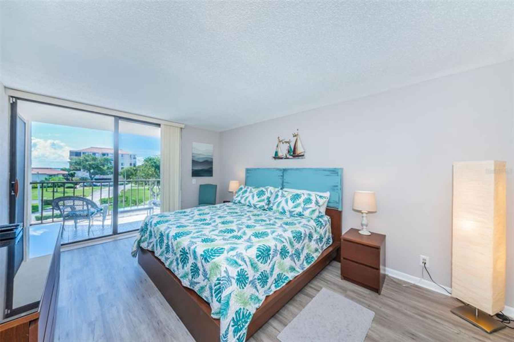 Master bedroom w/Tropical Views. Luxury vinyl plank flooring. Slider to balcony.