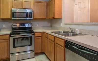 The kitchen features stainless appliances and a breakfast bar with a pass-thru window into the dinin